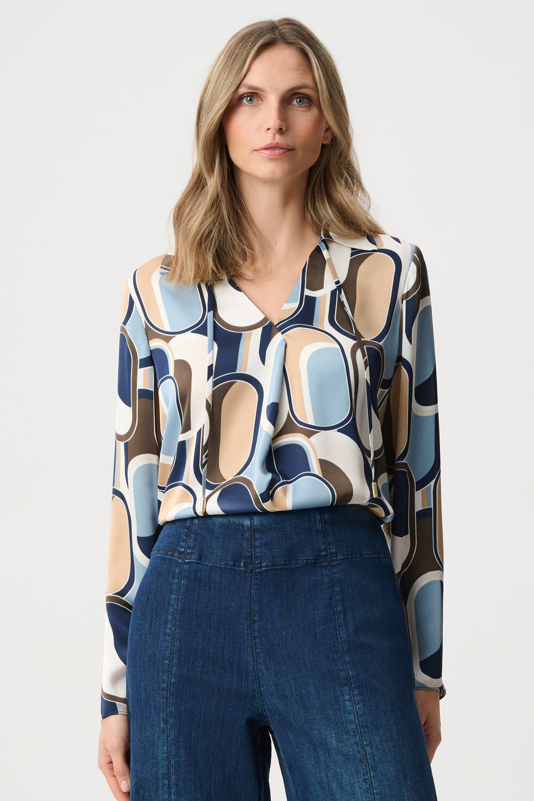 Woman wearing a patterned blouse and blue pants on a white background