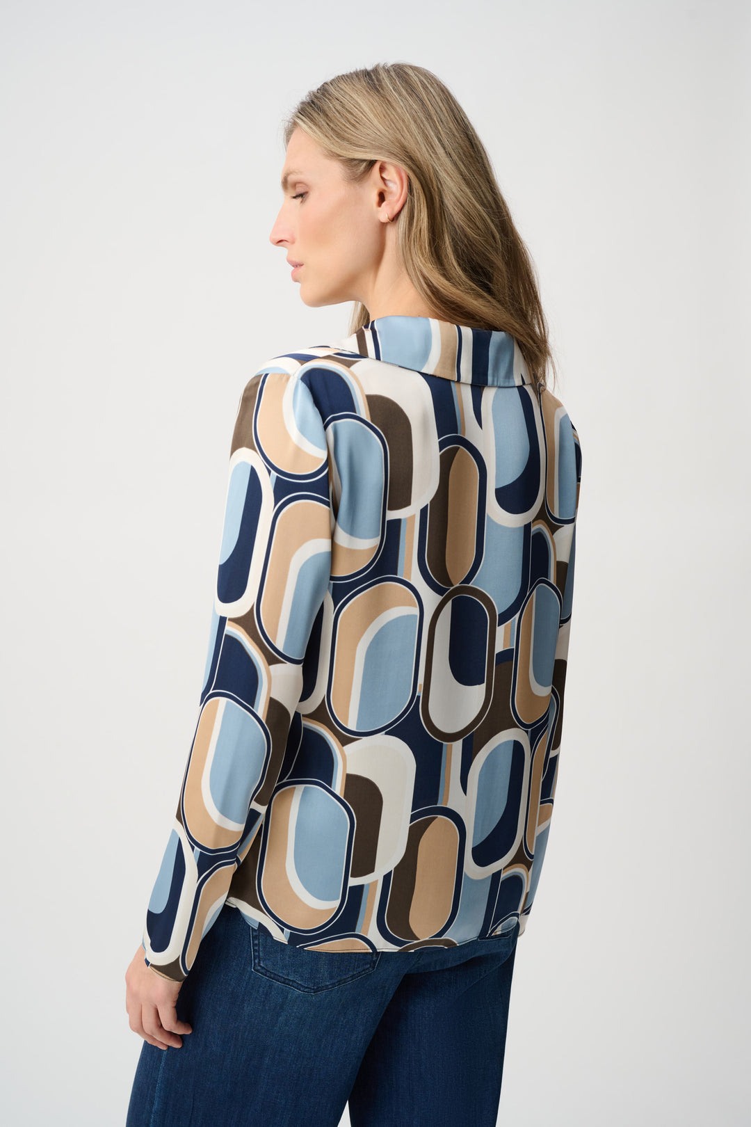 Woman wearing a patterned shirt with abstract design on a plain background