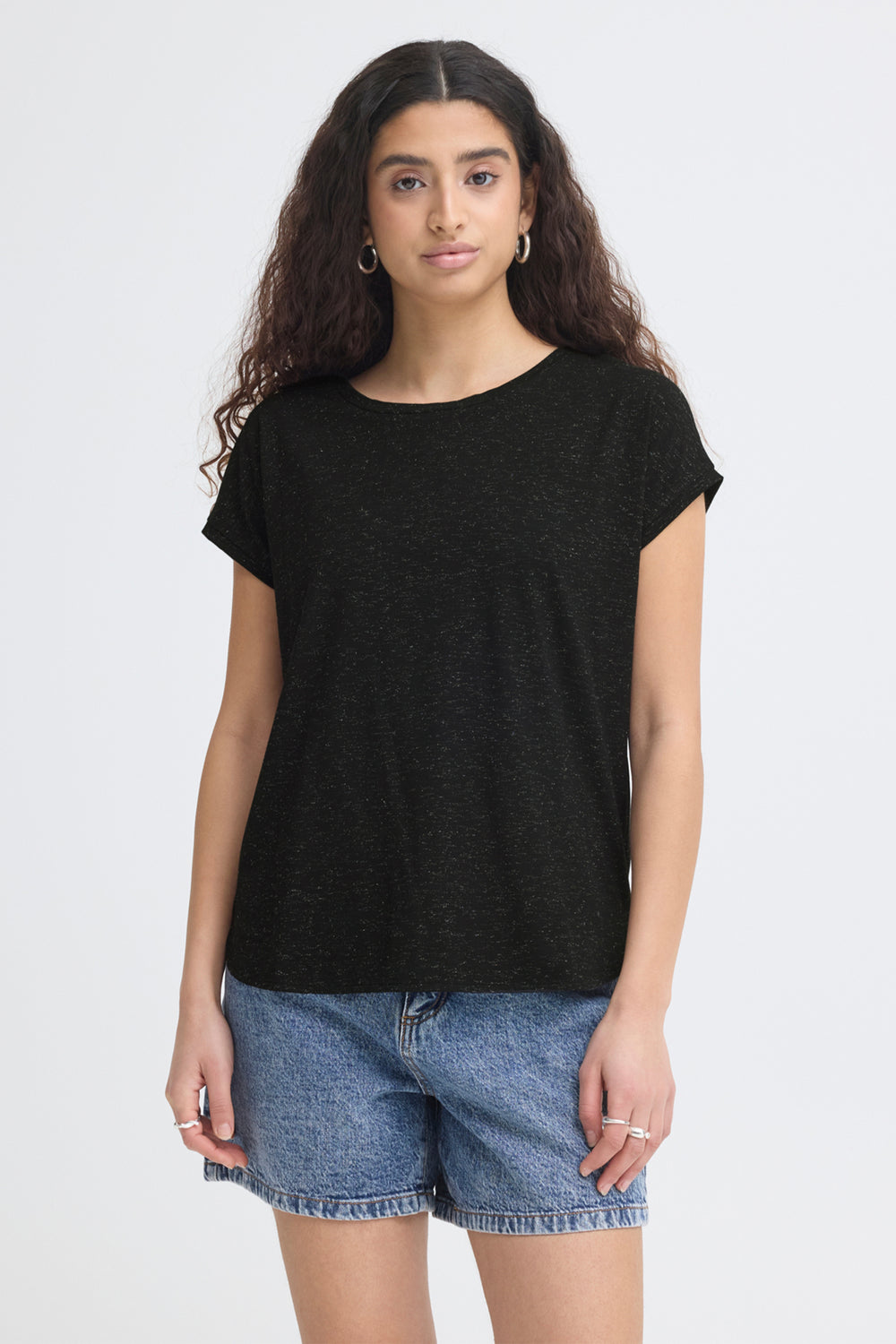 Woman wearing a black t-shirt and denim shorts on a white background