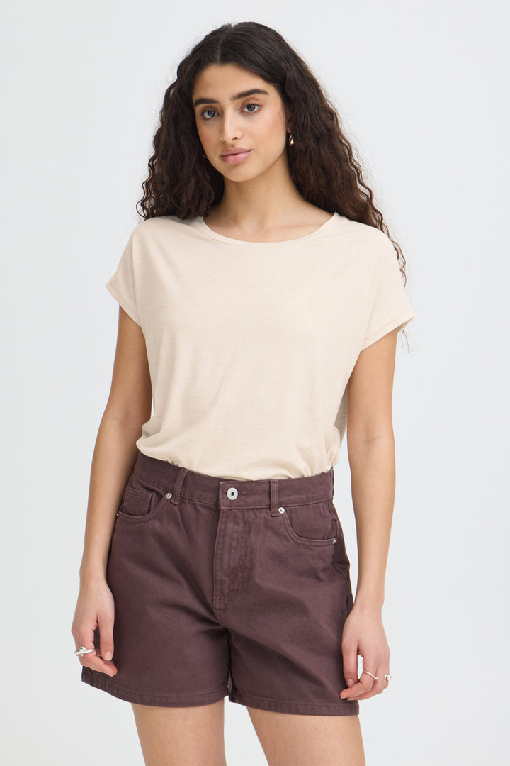 Woman wearing a beige top and brown shorts on a white background