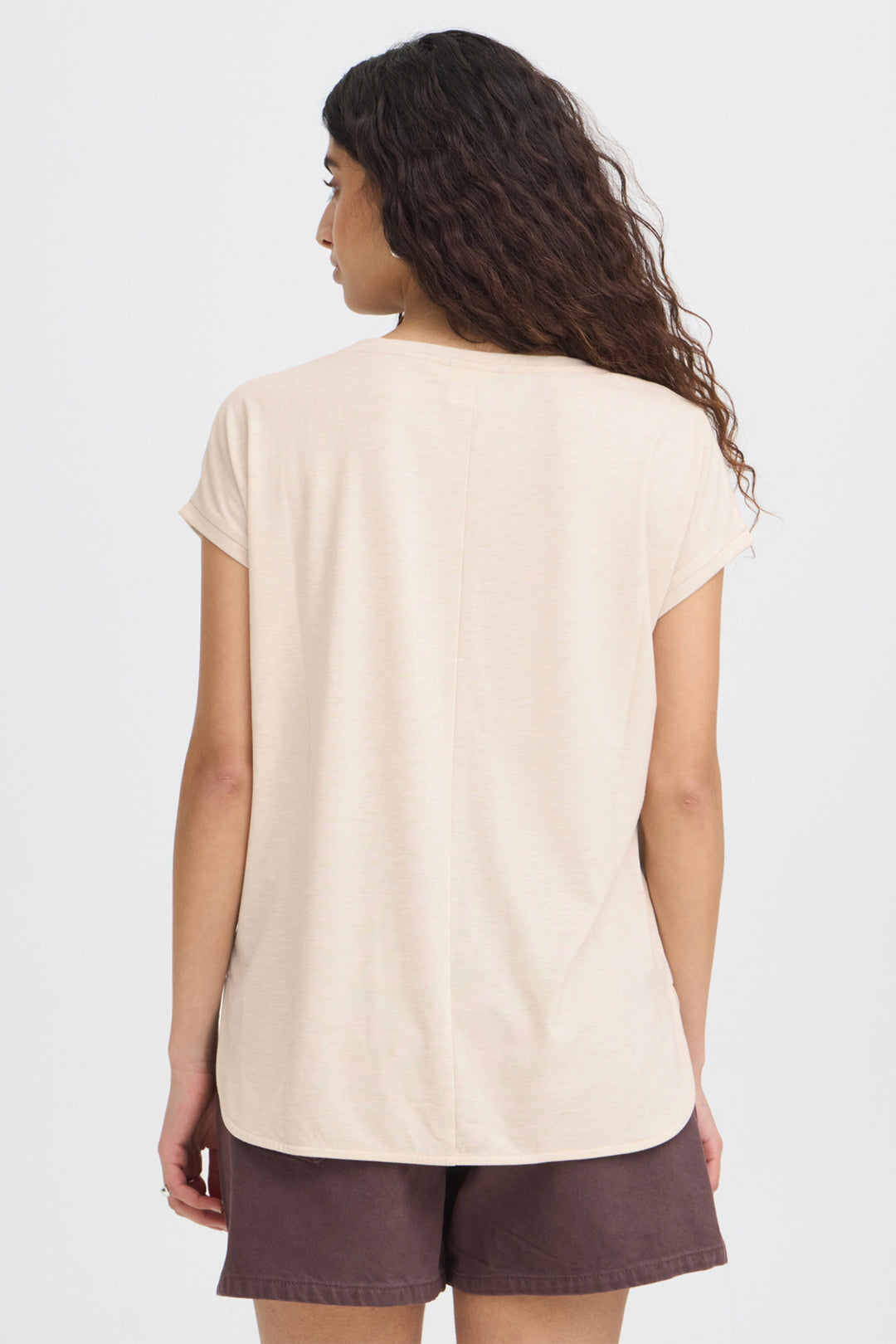 Woman wearing a beige t-shirt and brown shorts on a white background
