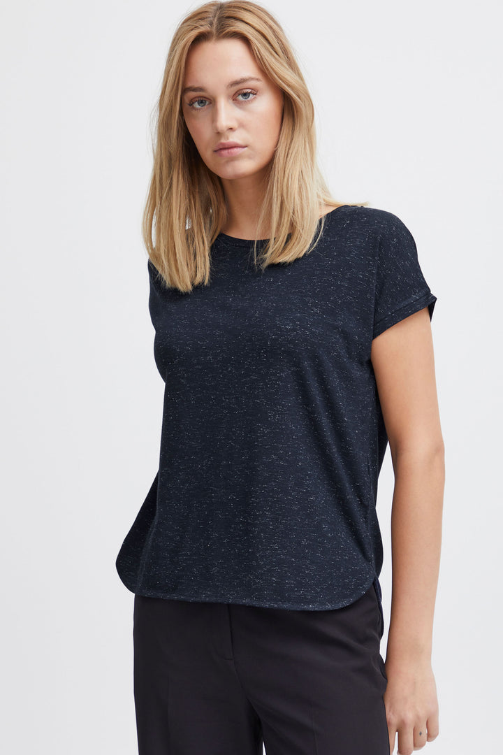 A woman wearing dark navy tshirt with short sleeves and a round neckline, paired with blue jeans.