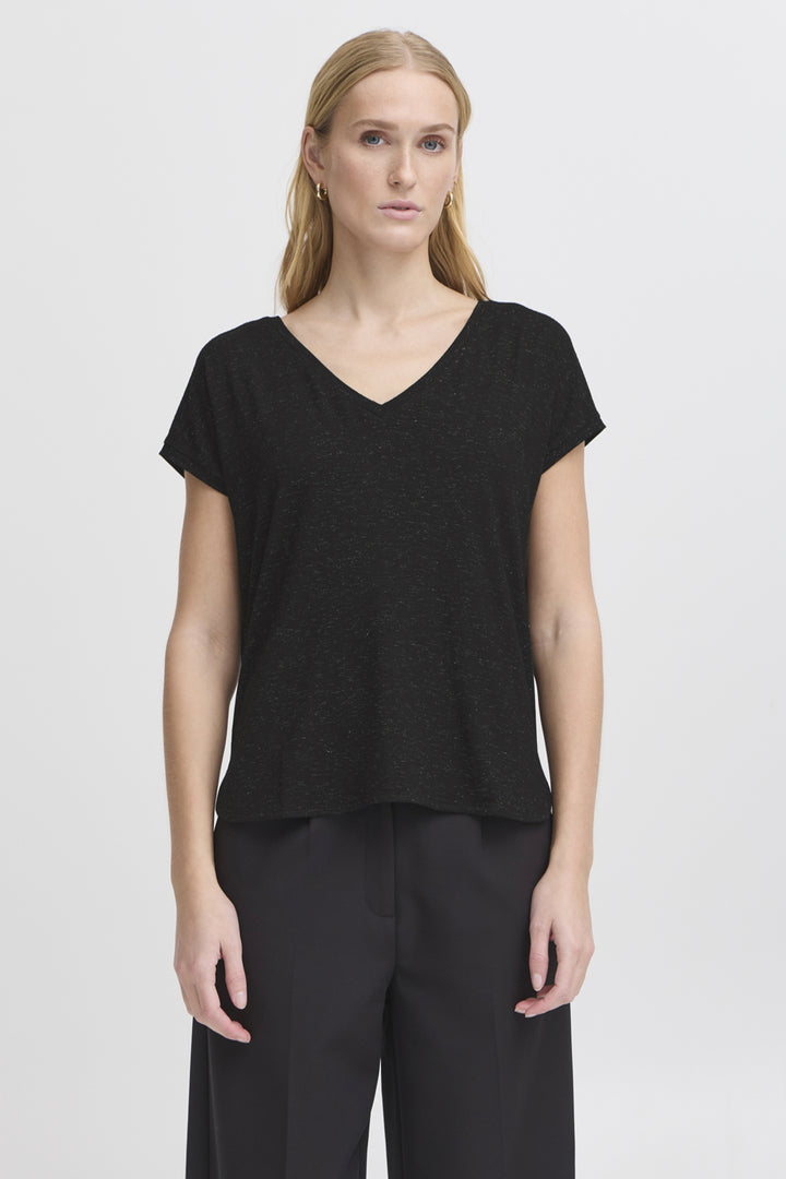 Woman wearing a black V-neck top and black pants on a white background