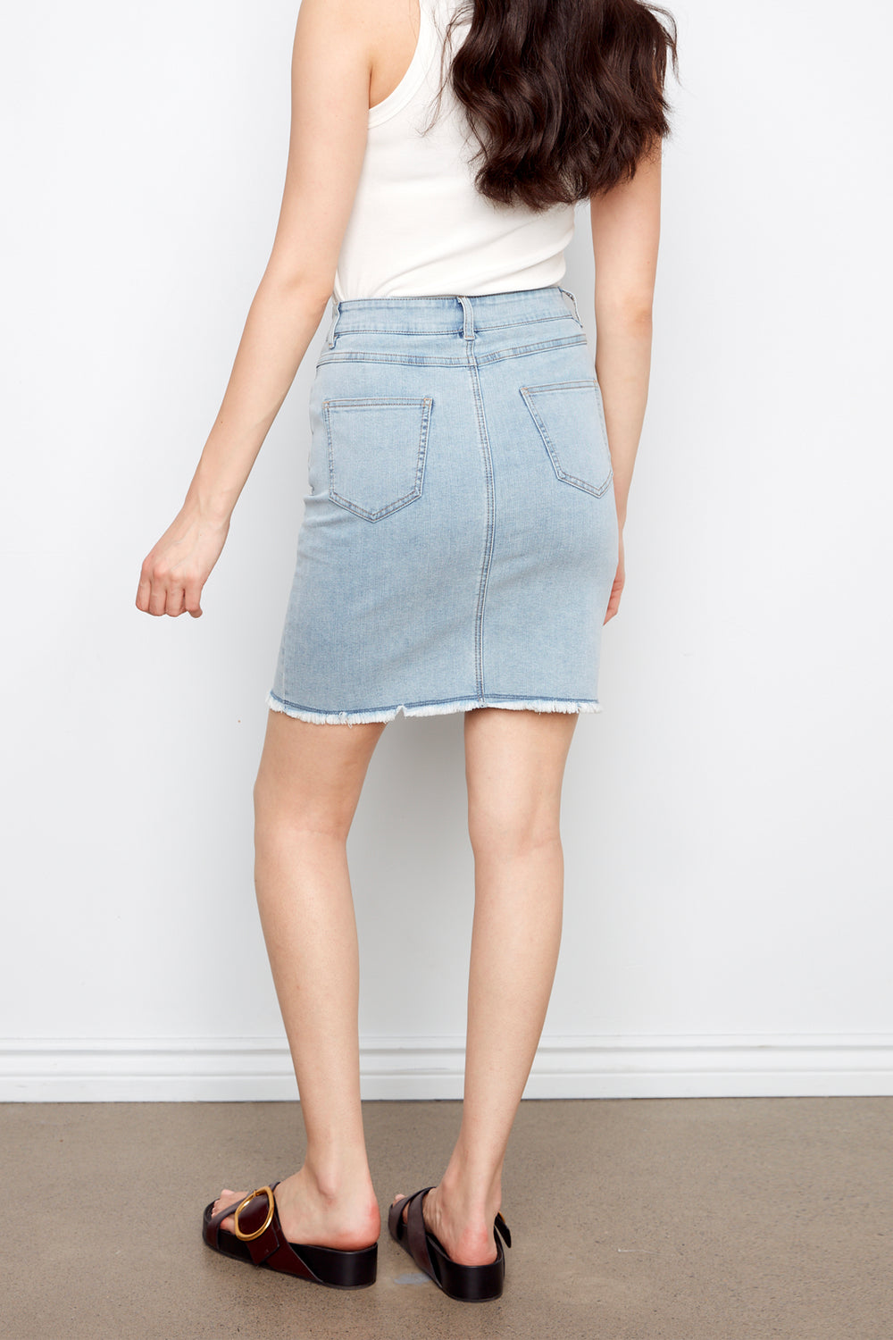Person wearing a light blue denim skirt against a white background