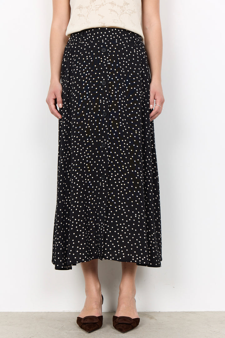 woman wearing a black midi skirt with white polka dots on a white background.