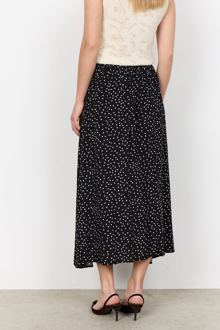 woman wearing a black midi skirt with white polka dots on a white background.