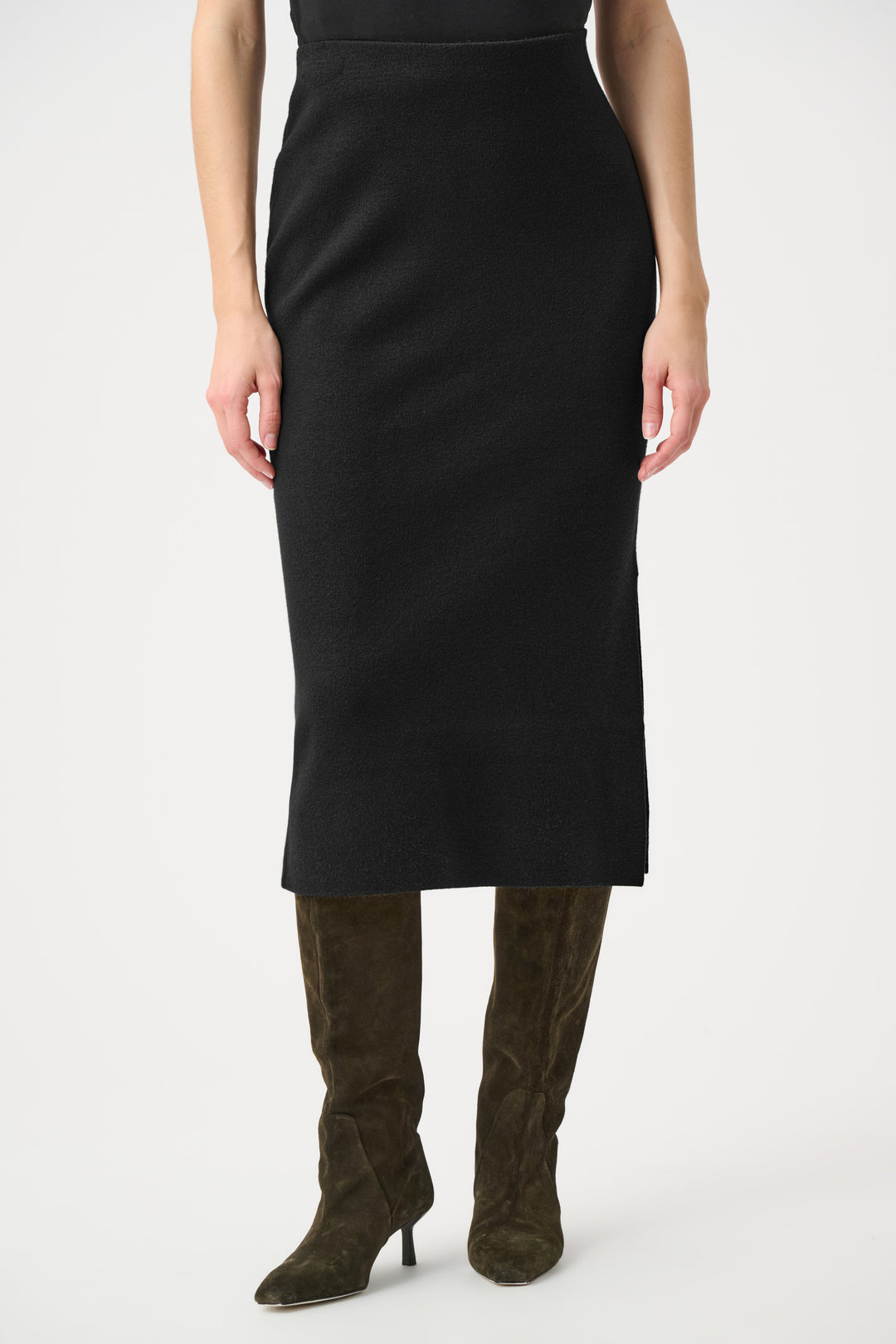 Person wearing a black pencil skirt with green high-heeled boots on a white background