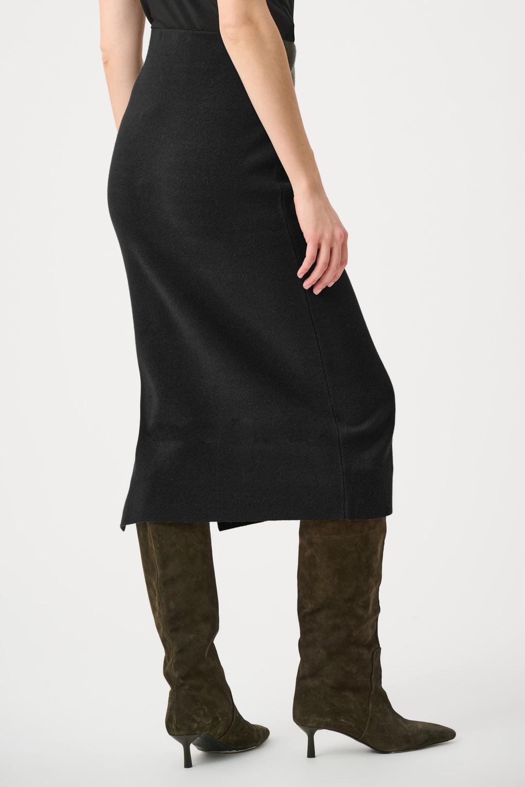 Person wearing a black dress and brown knee-high boots on a white background