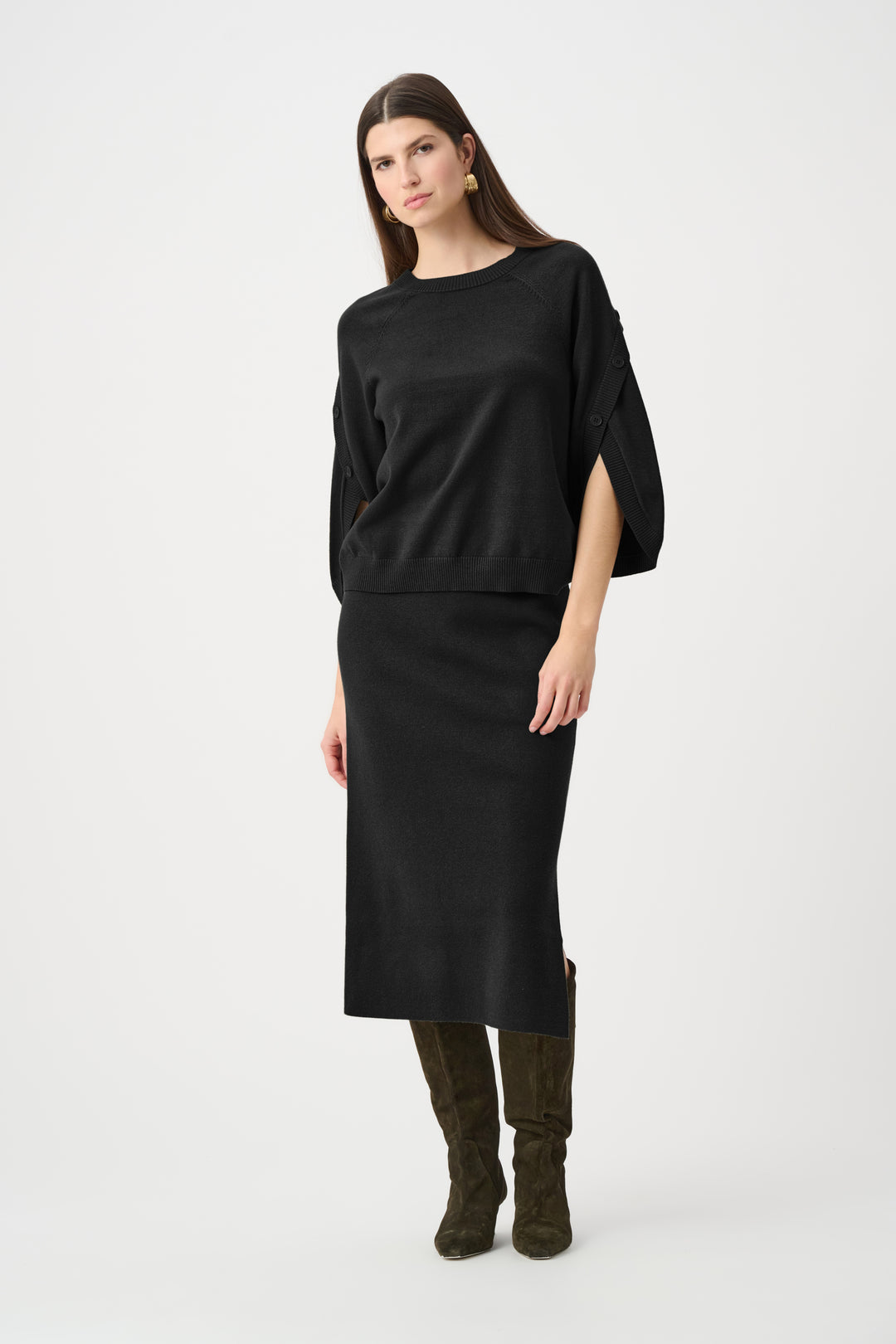Woman wearing a black skirt and sweater set and boots on a white background