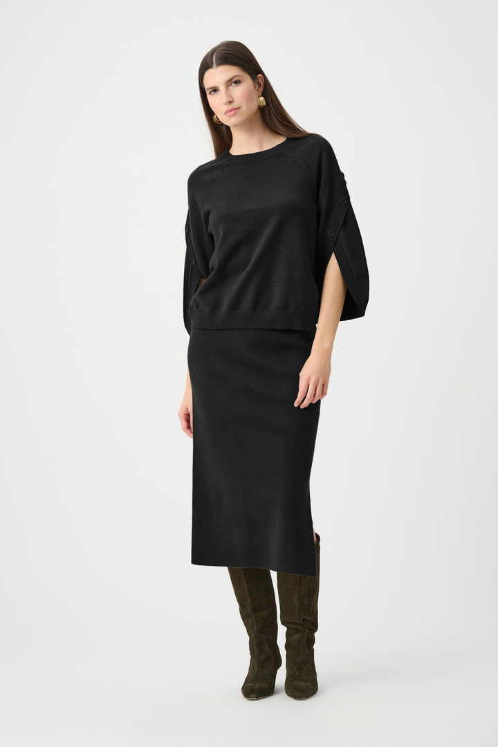 Woman wearing a black skirt and sweater set and boots on a white background