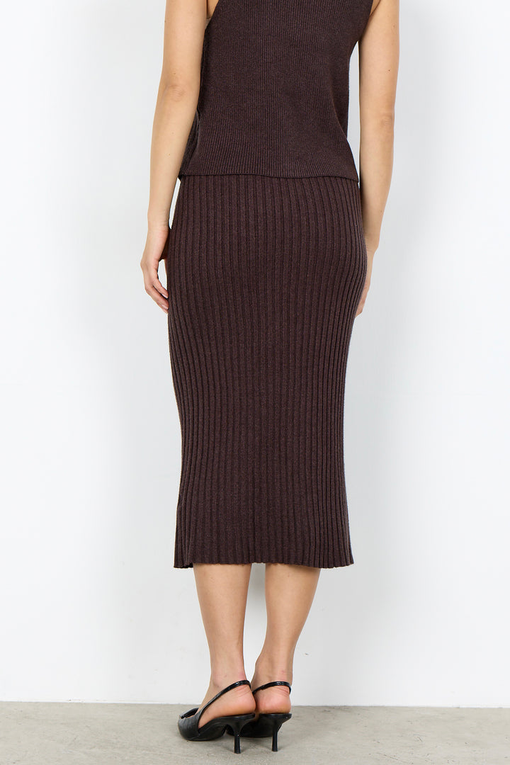 A model from the back wearing a dark brown ribbed knit midi skirt and a matching sleeveless top, paired with black high-heeled sandals, against a plain white studio background.