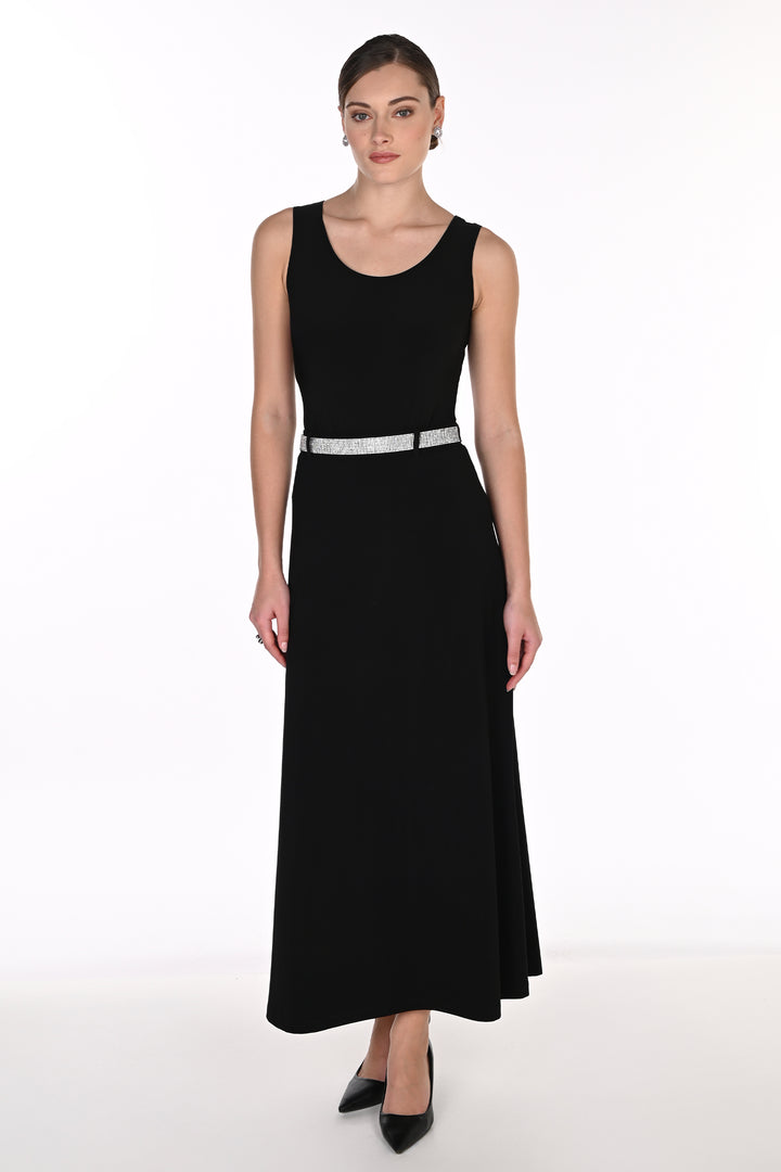 A woman modeling a black top, midi skirt with a high slit, and a silver embellished belt, paired with black pointed-toe heels against a white studio background.