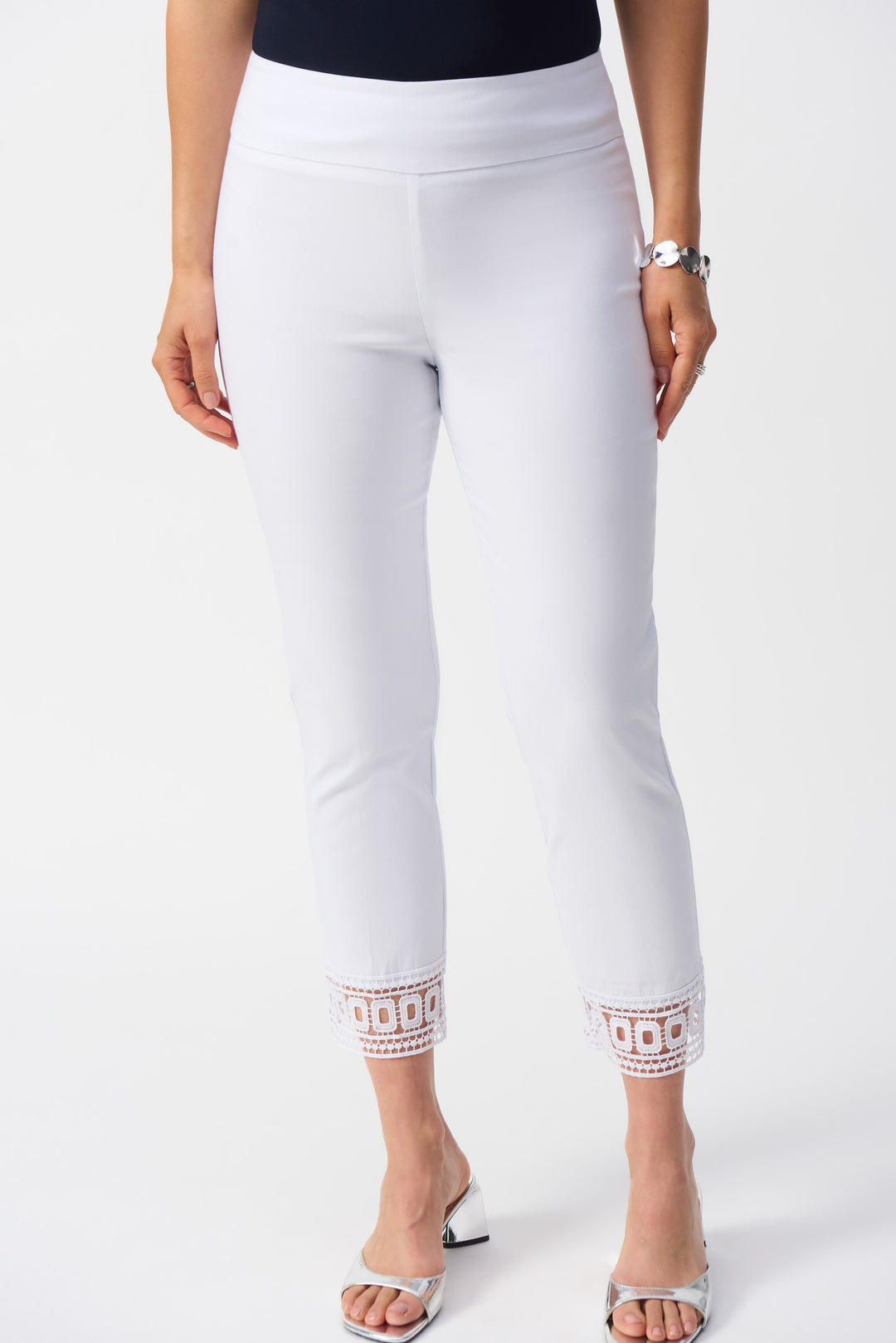 Joseph Ribkoff Spring 2025  These Crop Pants With Lace Hem are expertly crafted in Canada, combining a modern slim fit with a convenient pull-on elastic waist. The high-rise design is complemented by an embellished hem for a flattering silhouette. 