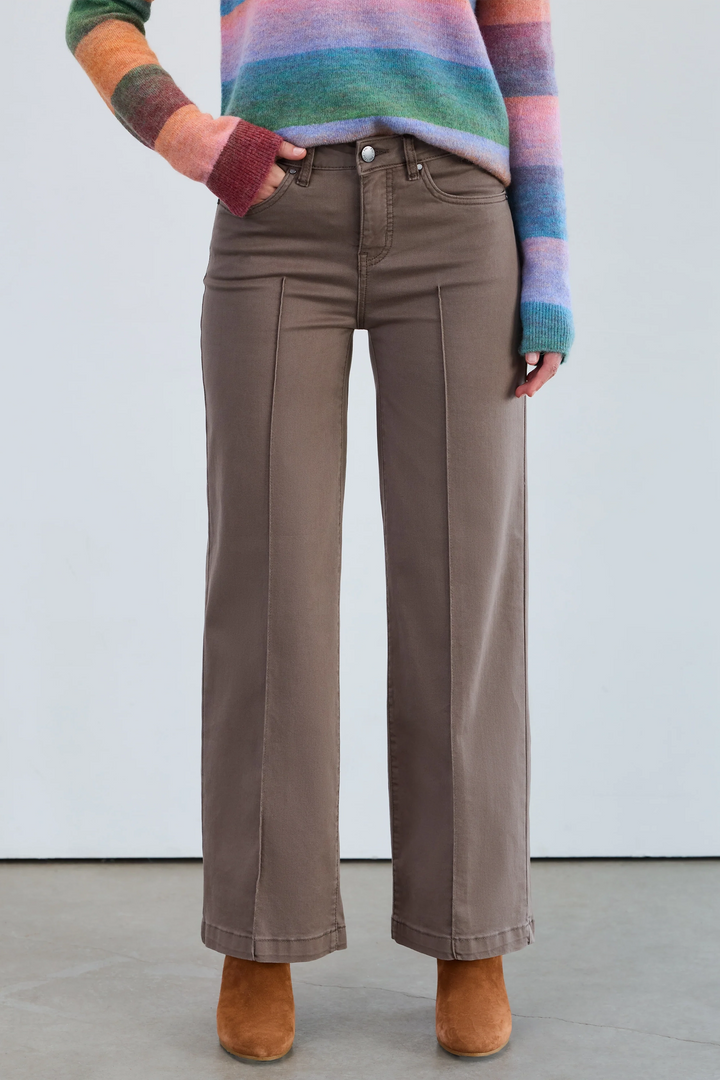 Person wearing brown wide-leg pants and a colorful sweater against a white background