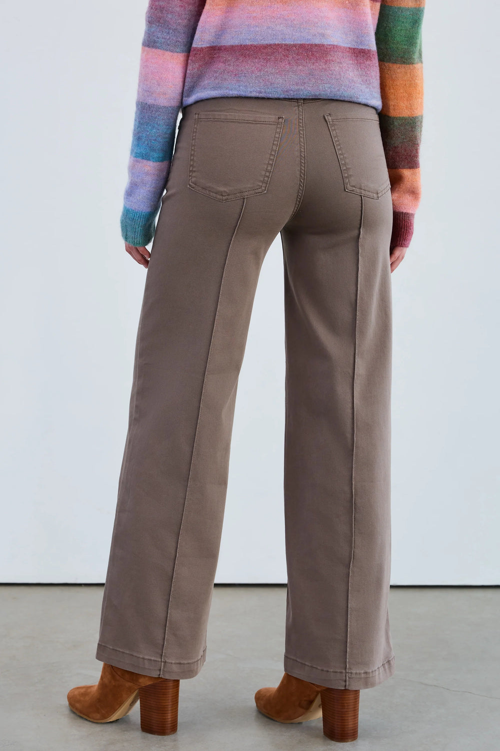 Person wearing brown pants and a colorful sweater against a white background