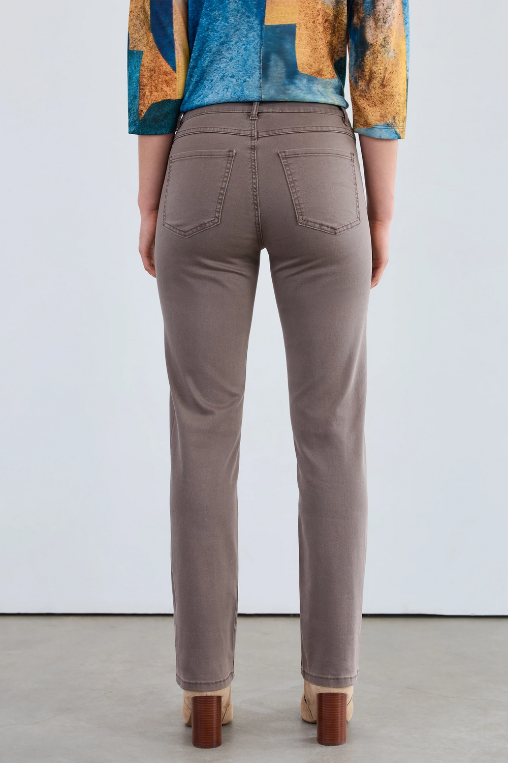 Person wearing brown pants with a colorful top against a white background