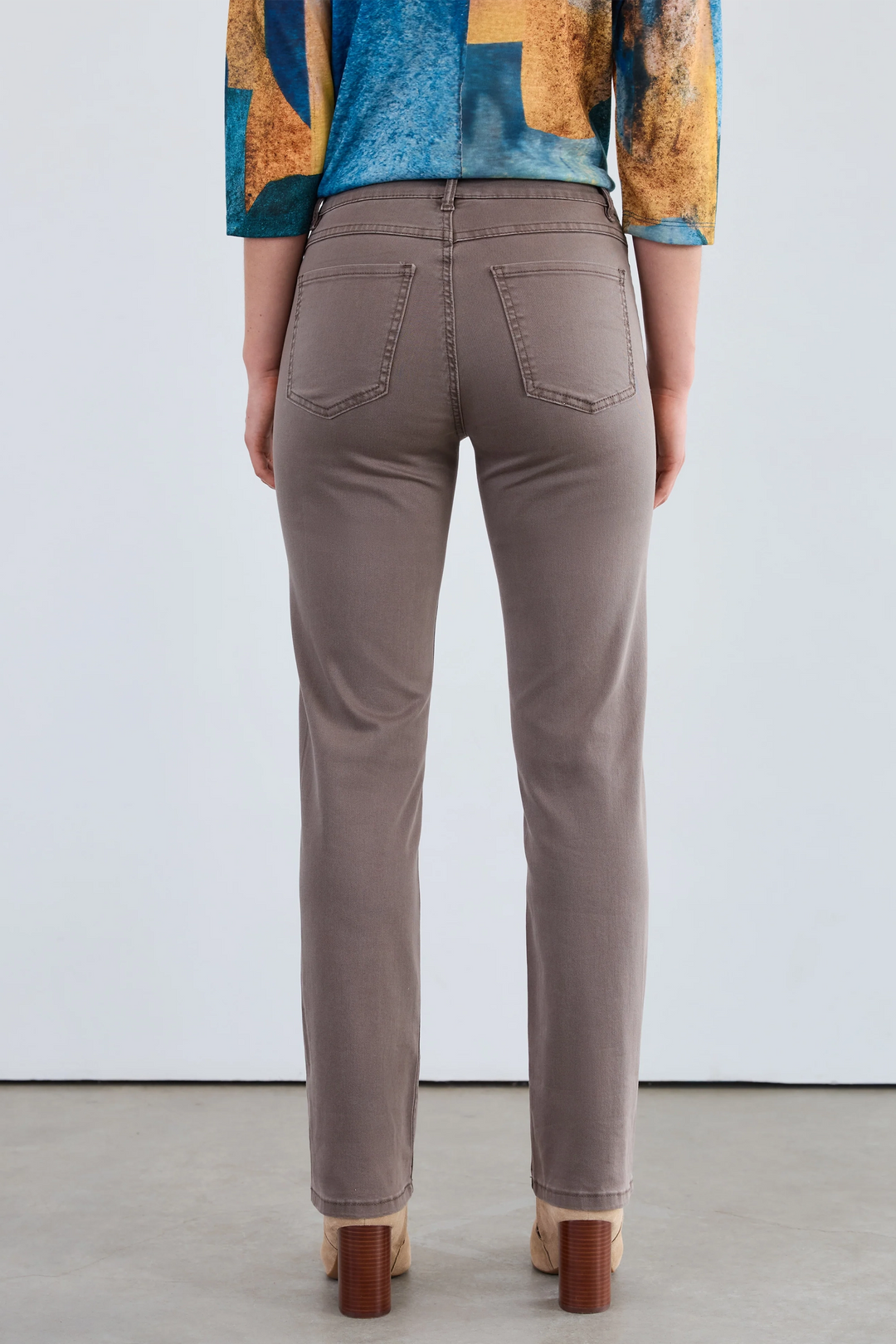 Person wearing brown pants with a colorful top against a white background