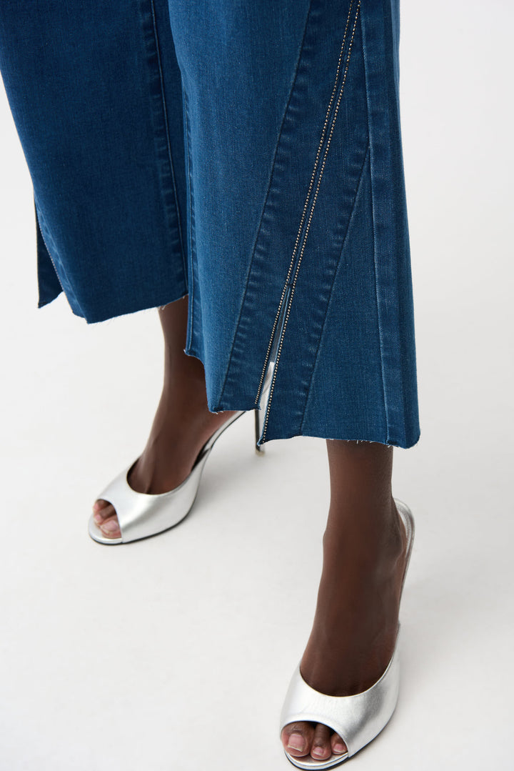 Person wearing blue jeans and silver high-heeled shoes on a white background