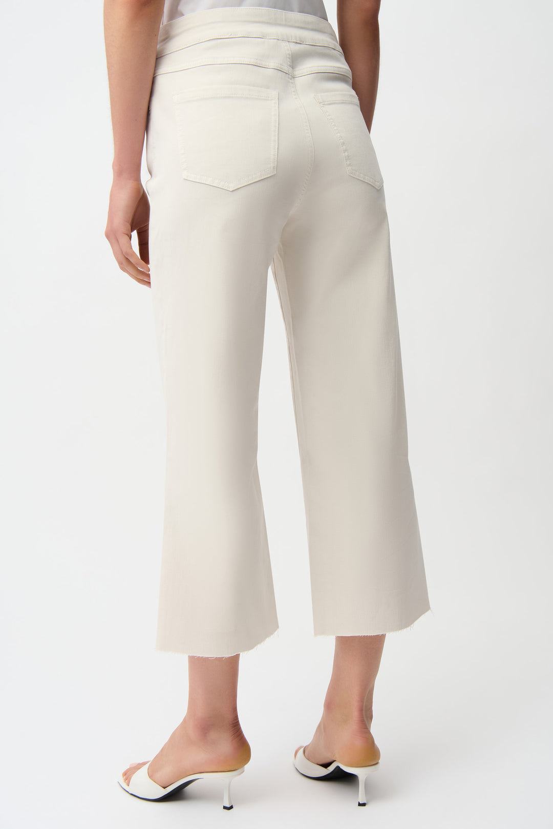 White capri pants worn by a person on a white background