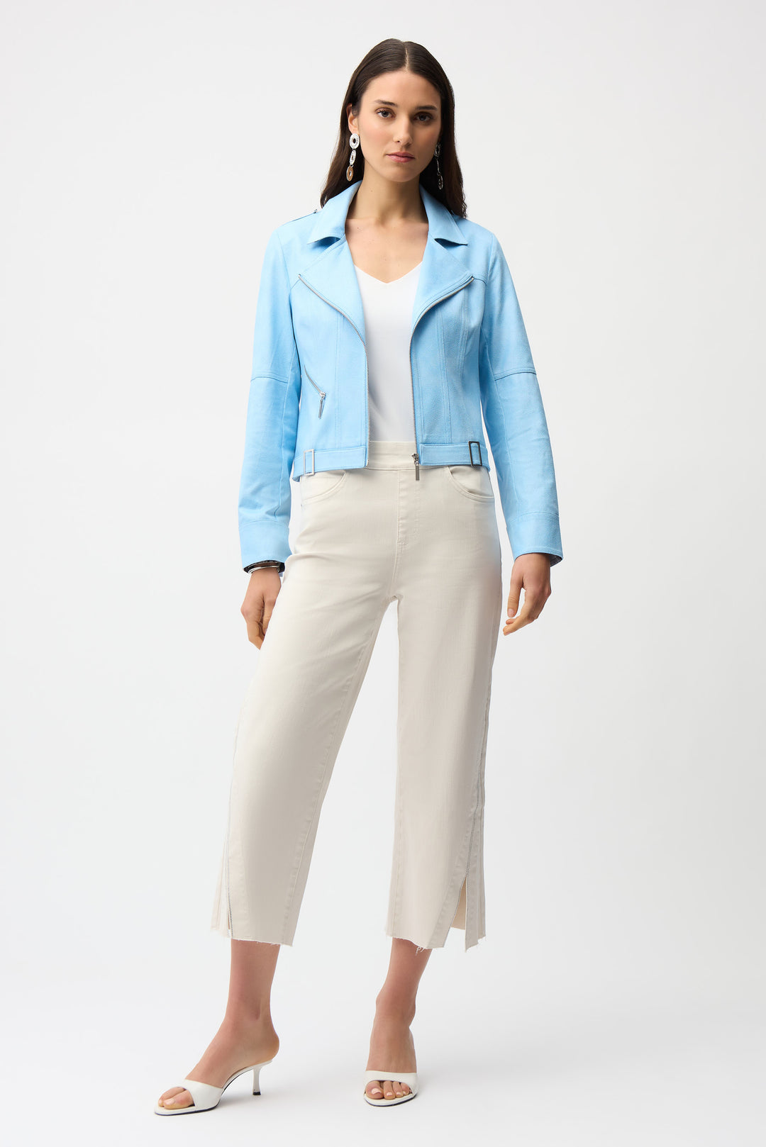 Woman wearing a light blue jacket, white top, and beige capri pants on a white background