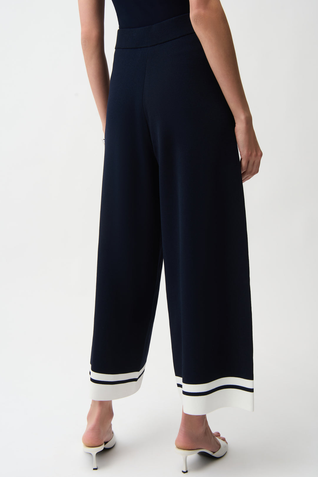 Navy blue pants with white trim hems worn by a person on a white background