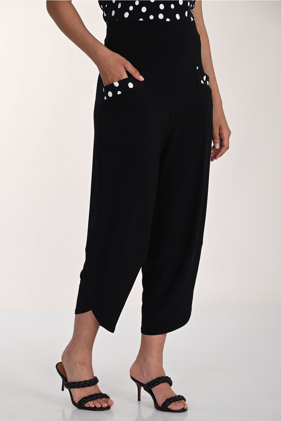 Person wearing black wide-leg pants with white polka dot trim on pockets on a white background