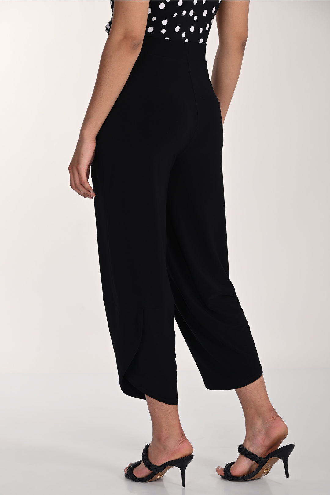 Person wearing black high-waisted wide-leg pants with a white background