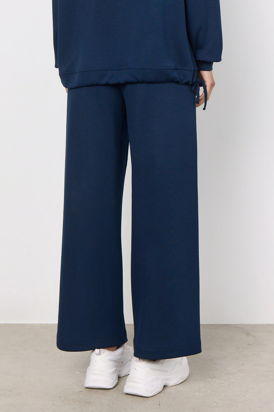 Person wearing navy blue pants and a matching top against a white background