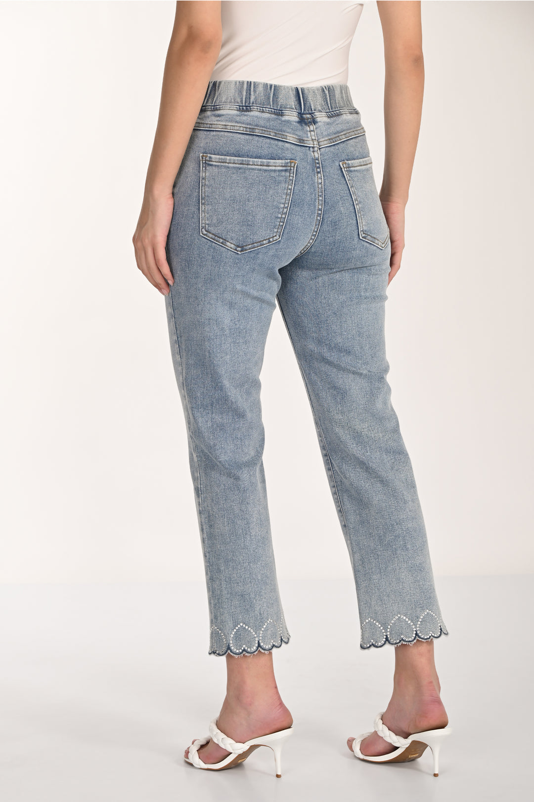 Light blue jeans with scalloped hem with hearts worn by a person on a white background