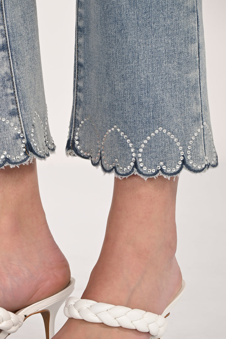 Close-up of denim pants with scalloped hem with hearts and white sandals on a light background