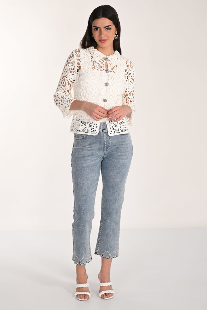 Woman wearing a white lace top and light blue jeans on a white background