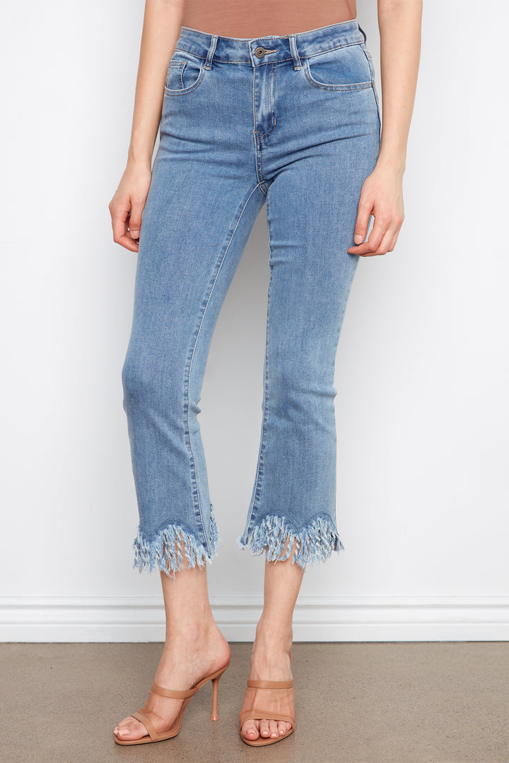 Light blue jeans with frayed hem worn by a person on a plain background