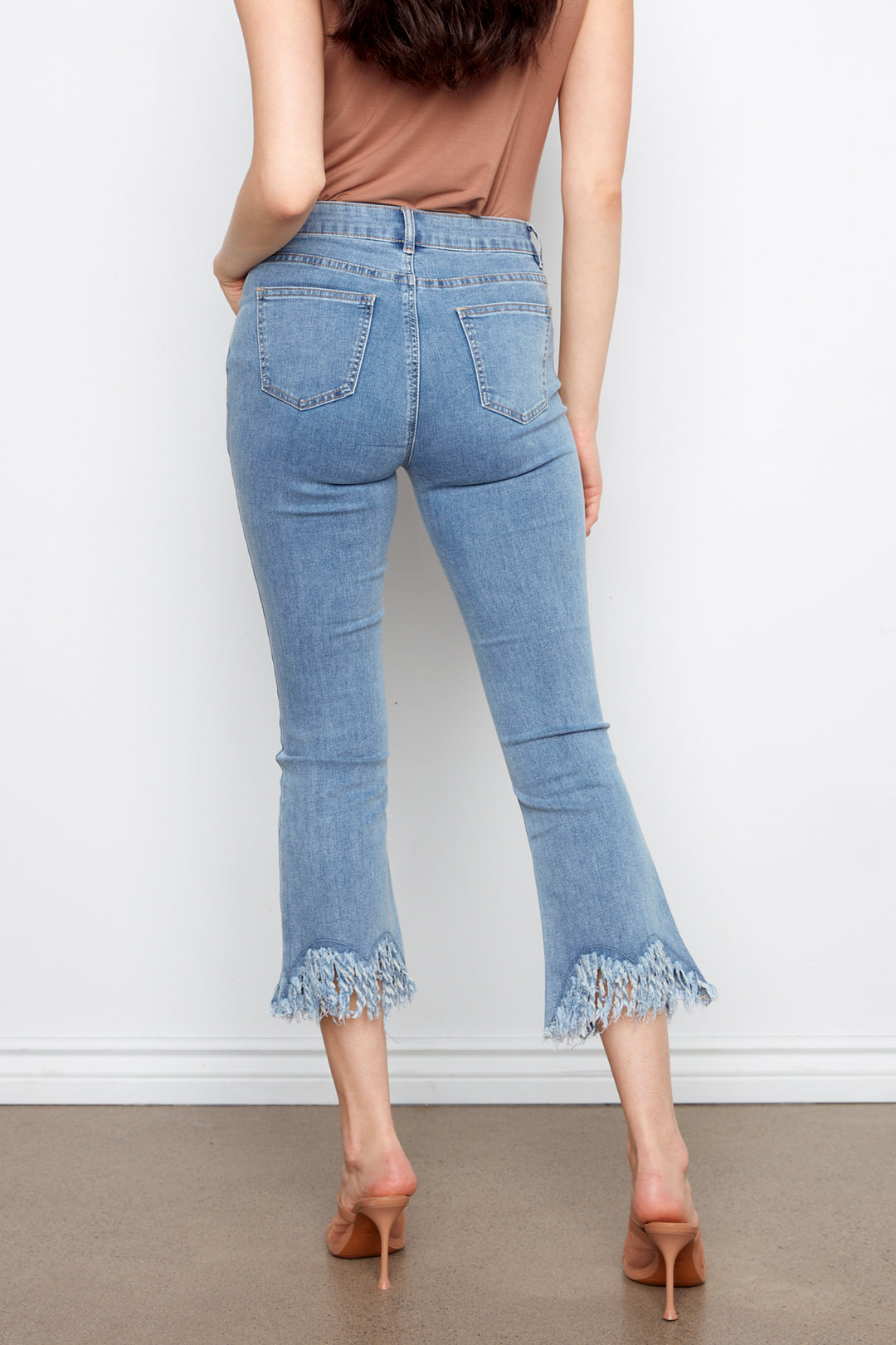 Light blue jeans with ruffled hem worn by a person on a plain background