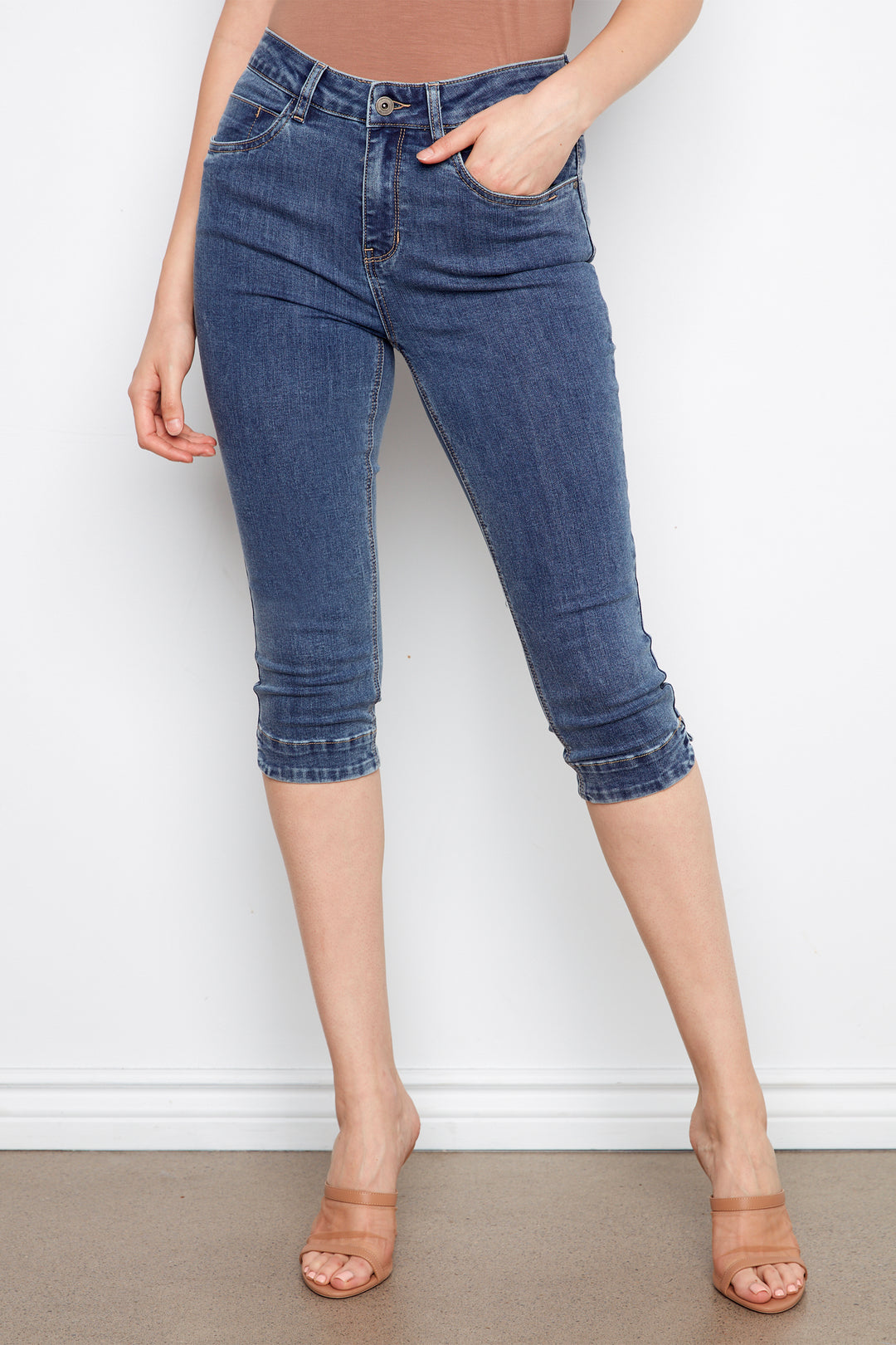 Person wearing blue denim capri pants against a white background