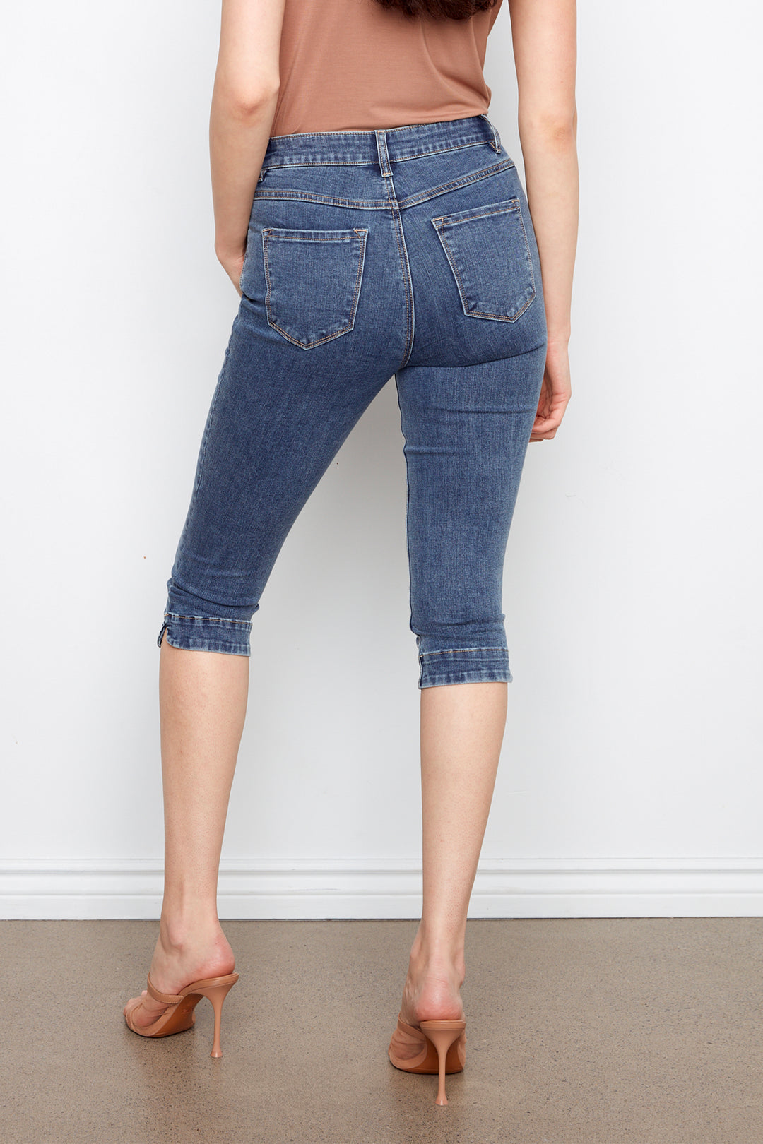 Person wearing blue denim capri pants against a white background