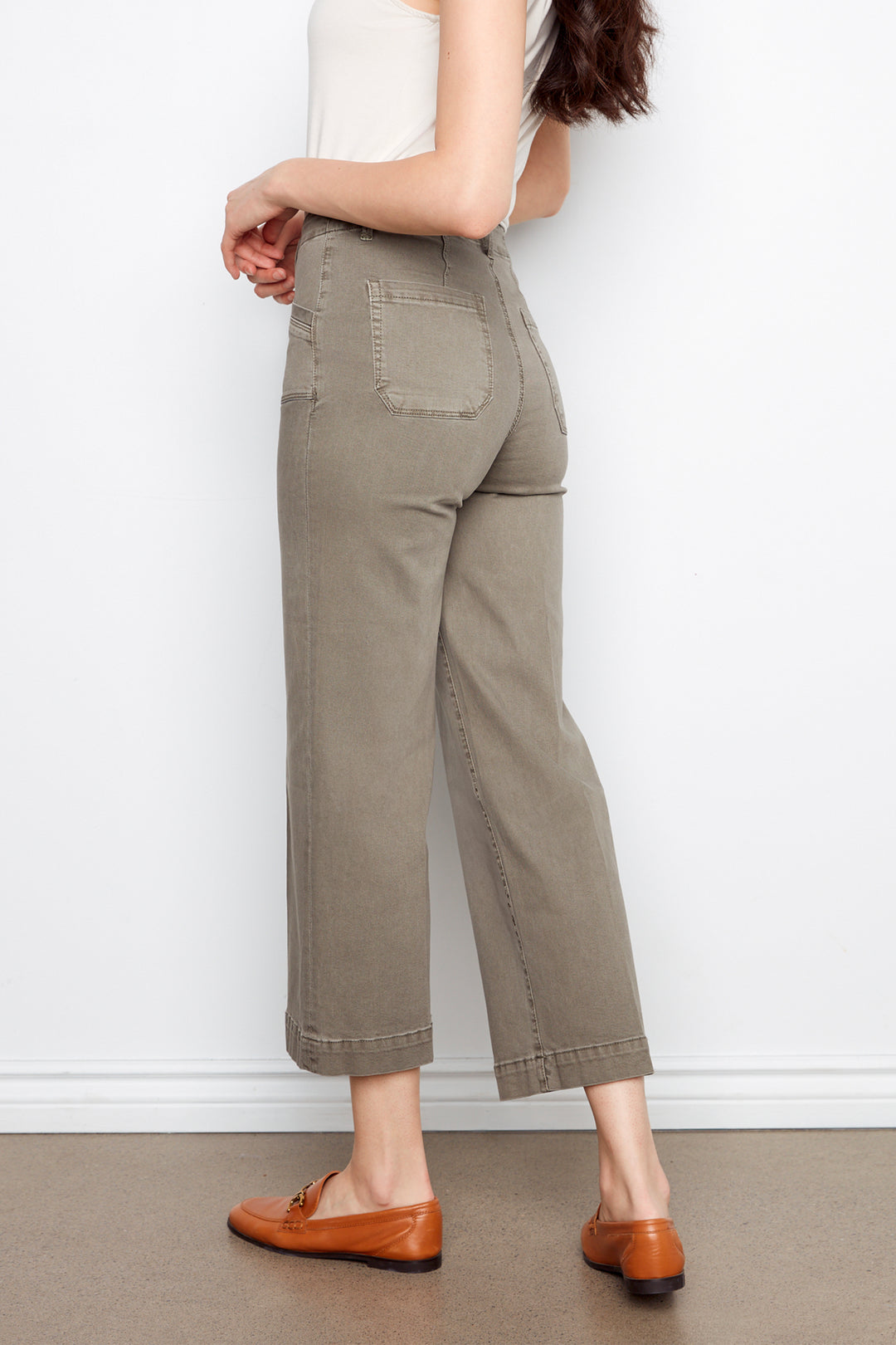 Person wearing beige pants and brown shoes on a plain background