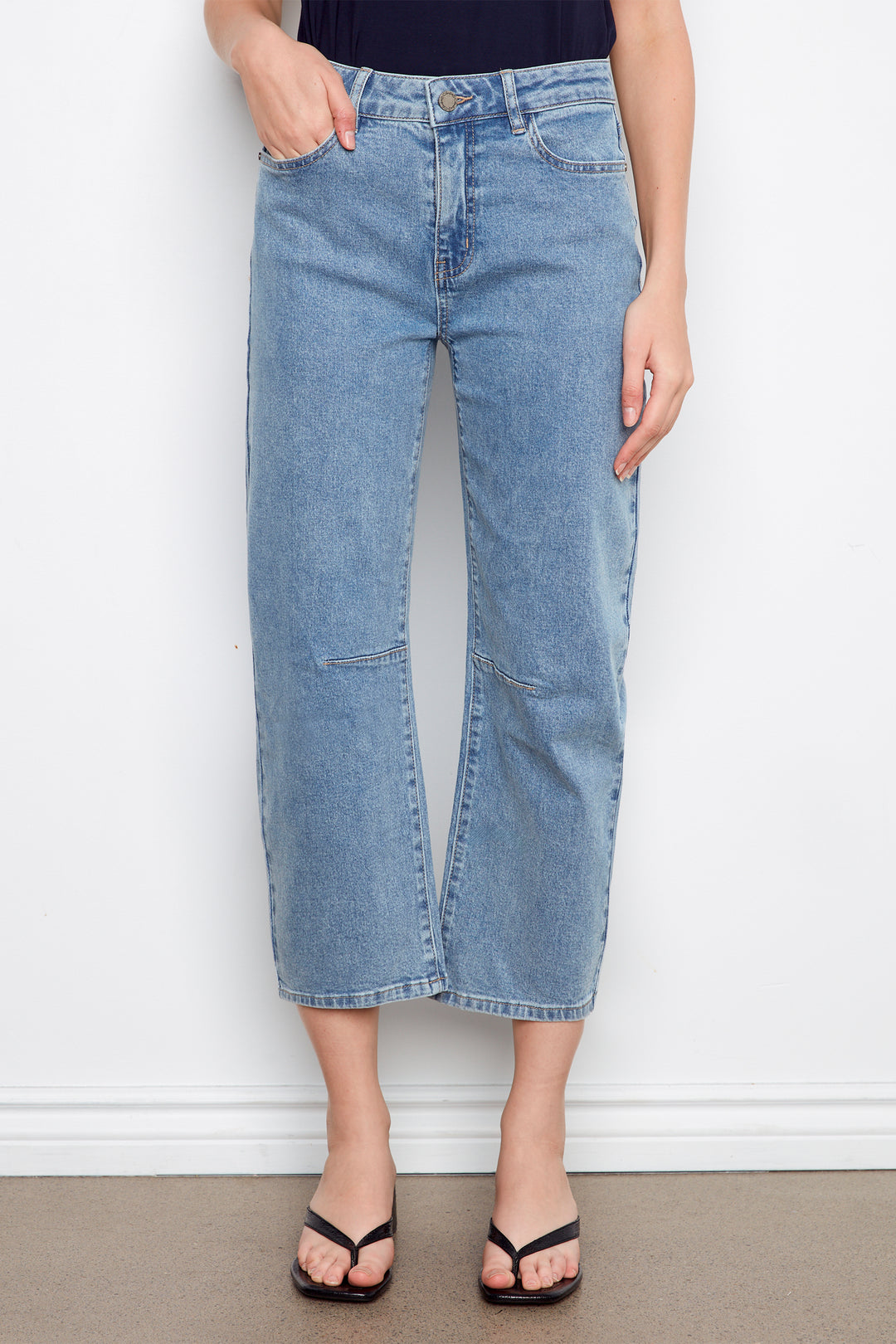 Person wearing light blue jeans against a white wall