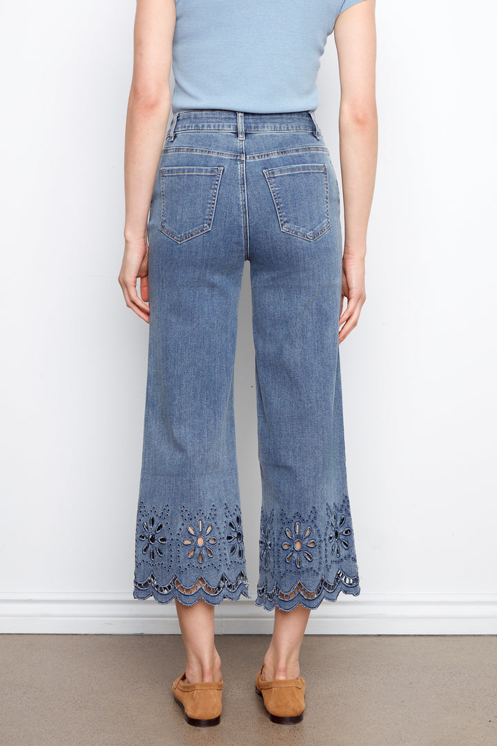 Person wearing blue jeans with lace details on a white background