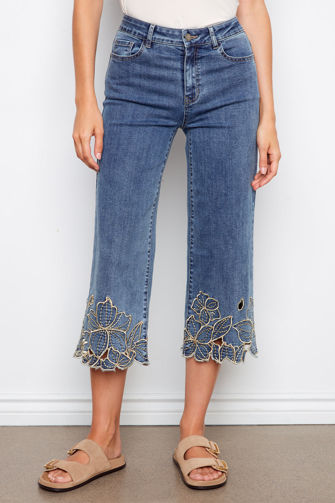 Blue jeans with floral lace cuffs worn by a person on a white background