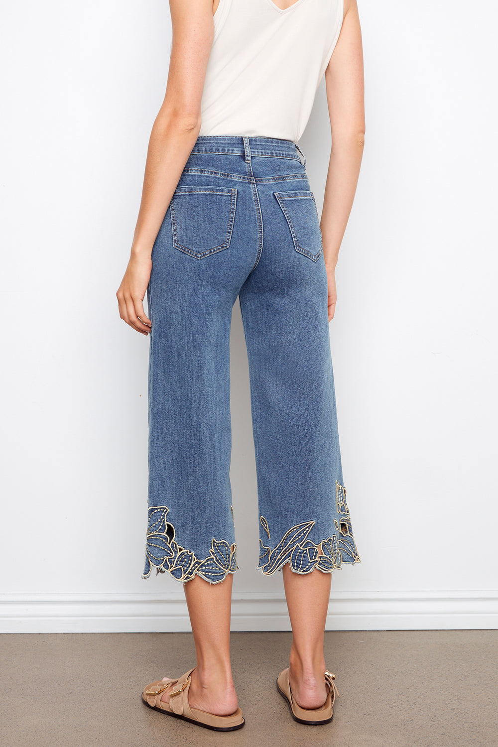 Person wearing blue jeans with lace trim on a white background