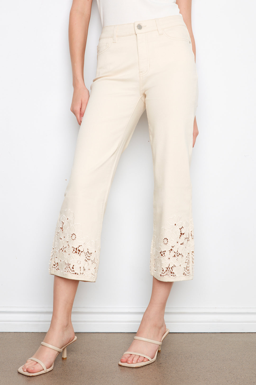 Person wearing cream-colored pants with floral embroidery against a white background