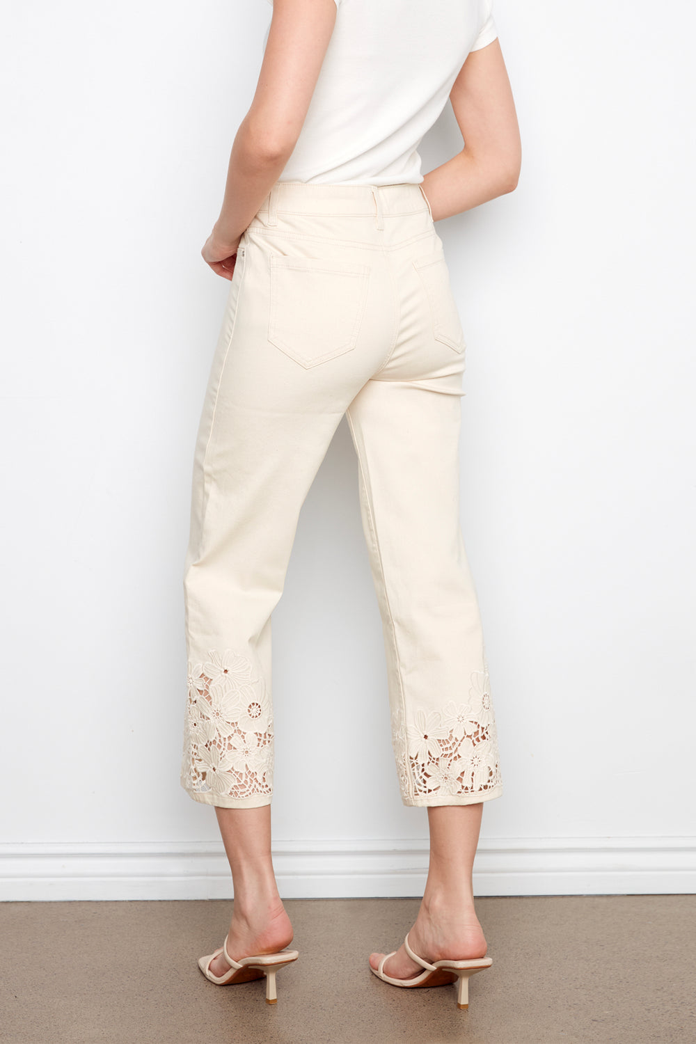 Person wearing cream-colored pants with lace details against a white background