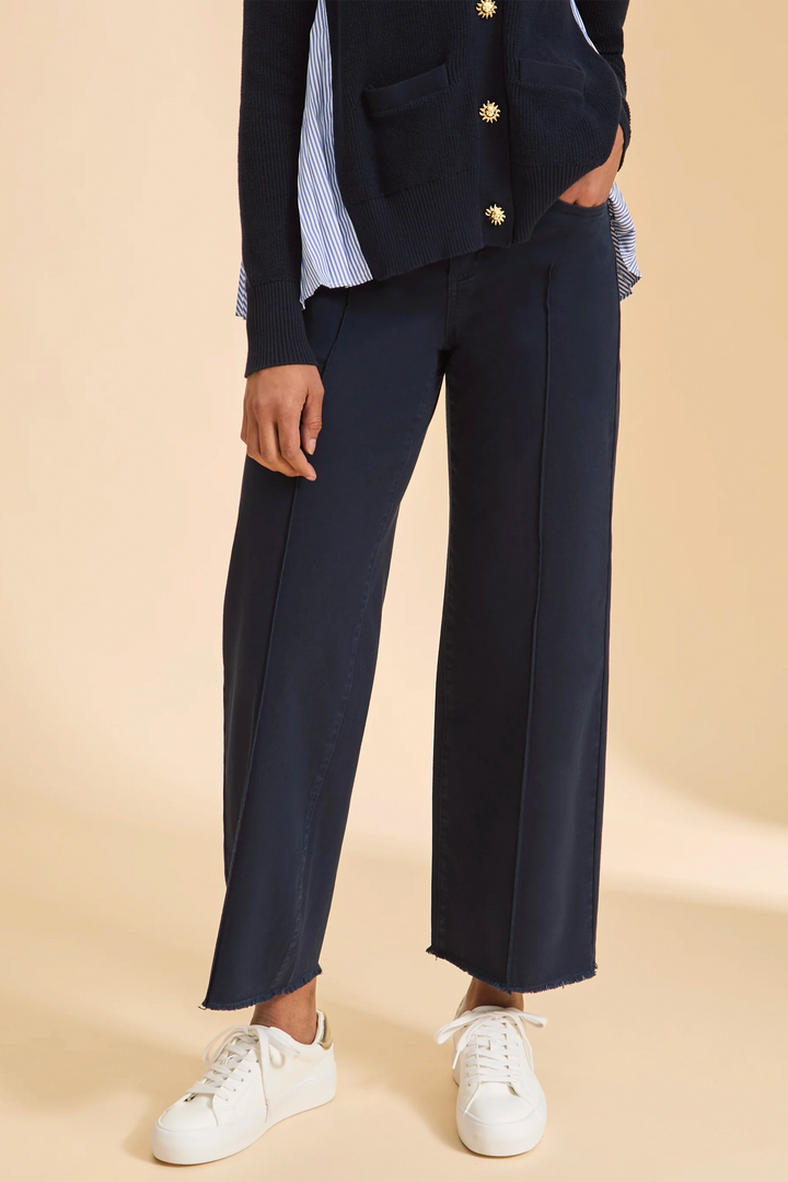 Person wearing a navy cotton jeans with white sneakers on a beige background