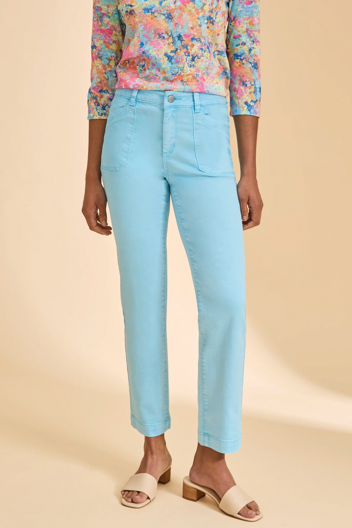 Person wearing light blue jeans and a colorful floral top on a beige background