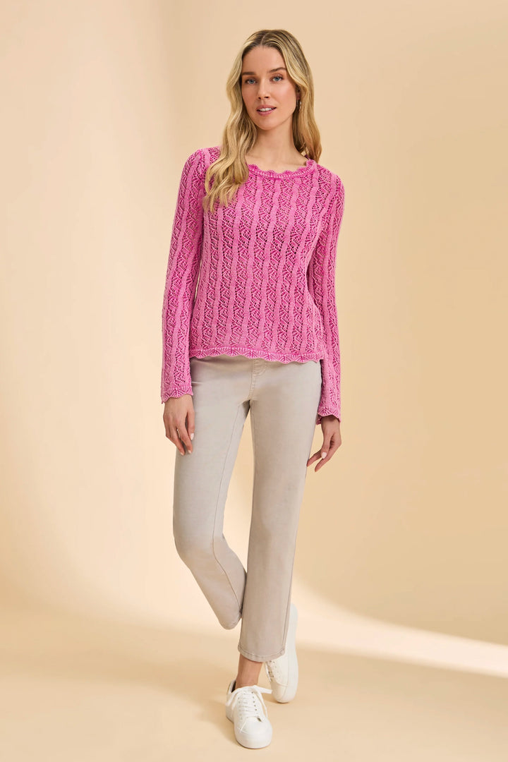 Woman wearing a pink knitted sweater and beige pants on a beige background