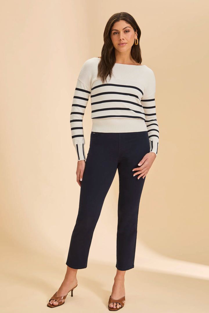 Woman wearing a striped sweater and navy pants on a beige background