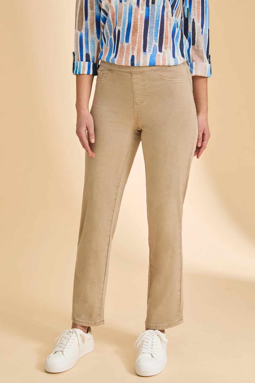 Person wearing beige pants and a patterned shirt on a beige background