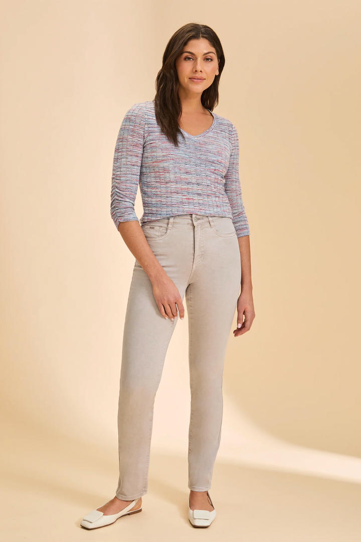 Woman wearing a patterned top and beige pants on a beige background