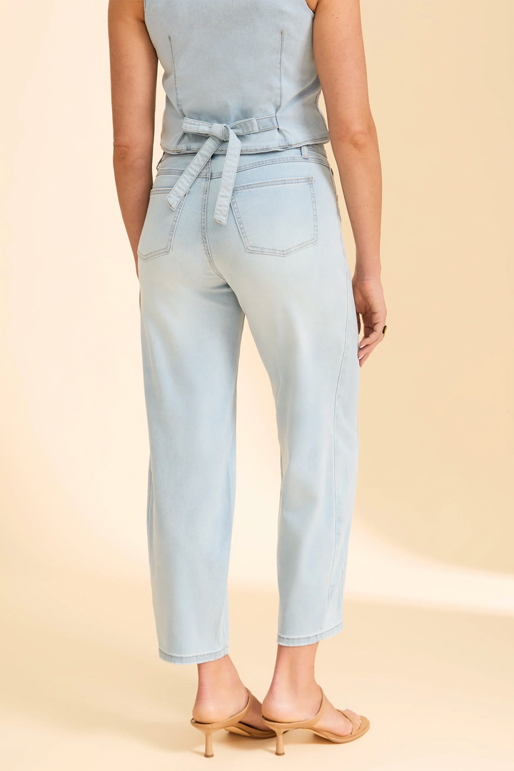 Light blue sleeveless top and jeans worn by a person on a beige background