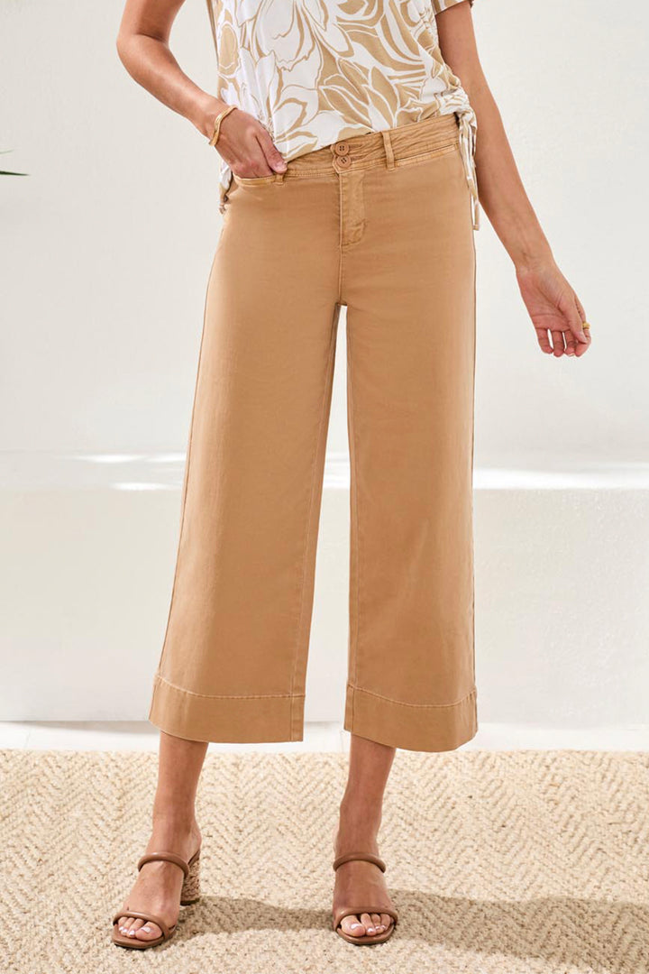 Person wearing beige wide-leg pants and a patterned top on a neutral background